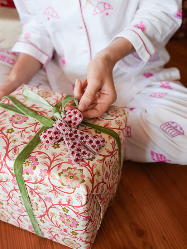 Person in pajamas sitting on a bed with a wrapped gift