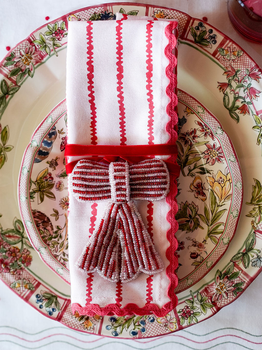 Christmas napkin with red and white stripes and a decorative beaded bow ornament