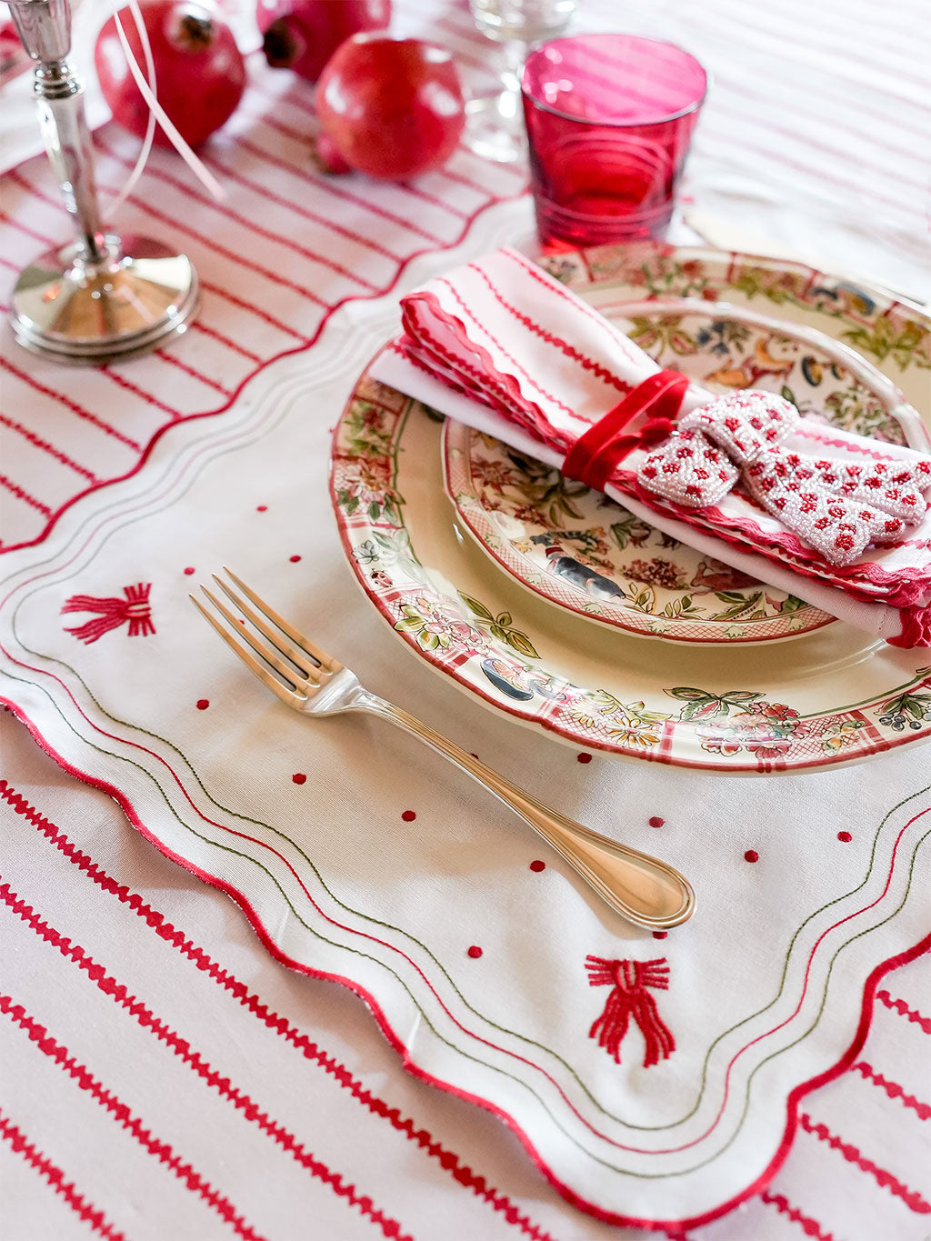 Decorative table setting with red and white theme, including plates, napkins, and cutlery.