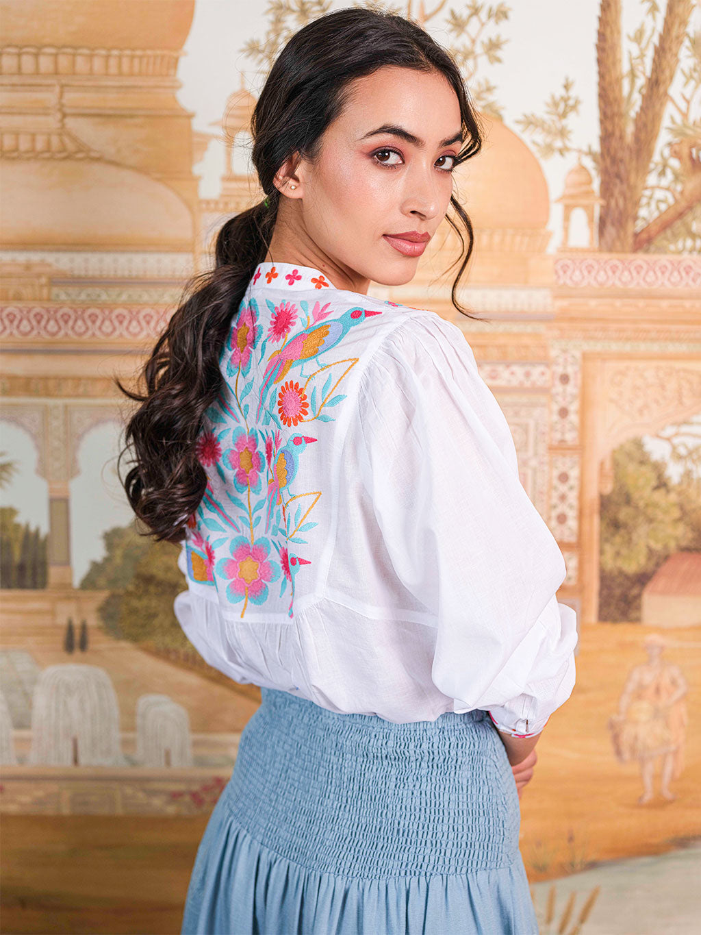 The stunning back view of the Catnep blouse showcasing a large-scale, colorful hand-guided embroidery of birds and flowers.