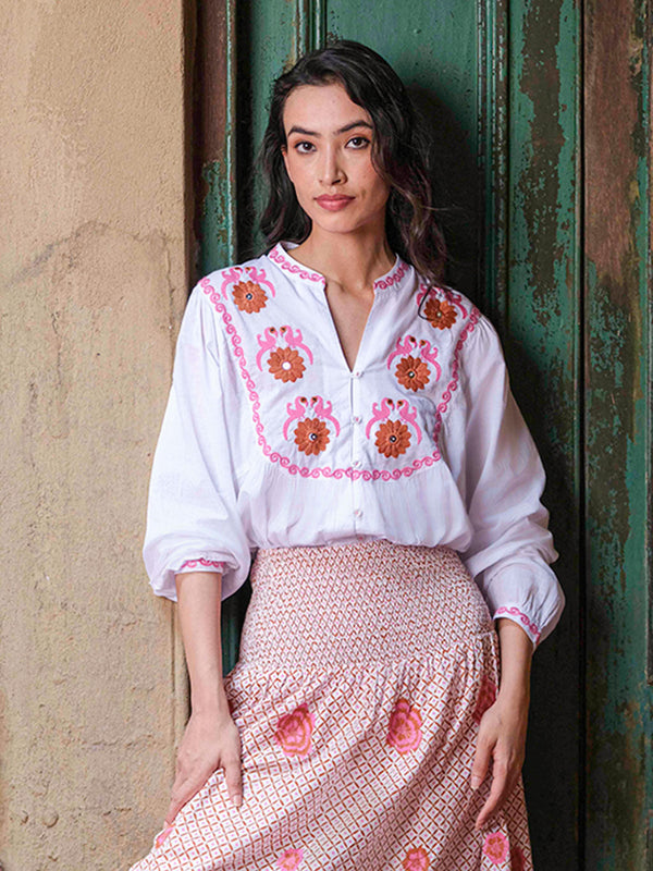 White organic cotton Catnep blouse by Nimo With Love featuring vibrant bird and floral embroidery on the front yoke.