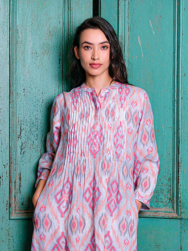 Detailed shot of the artisanal vertical pleats and the vibrant pink sorbet ikat pattern on the Woodruff dress.
