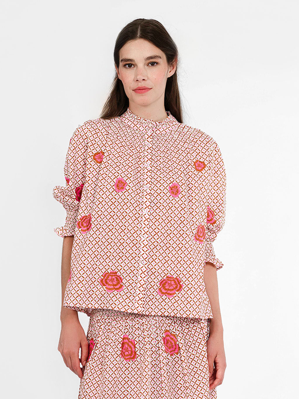 Model wearing the Bergamot blouse in grid-ikat organic cotton with pink peony embroidery and a smocked collar.