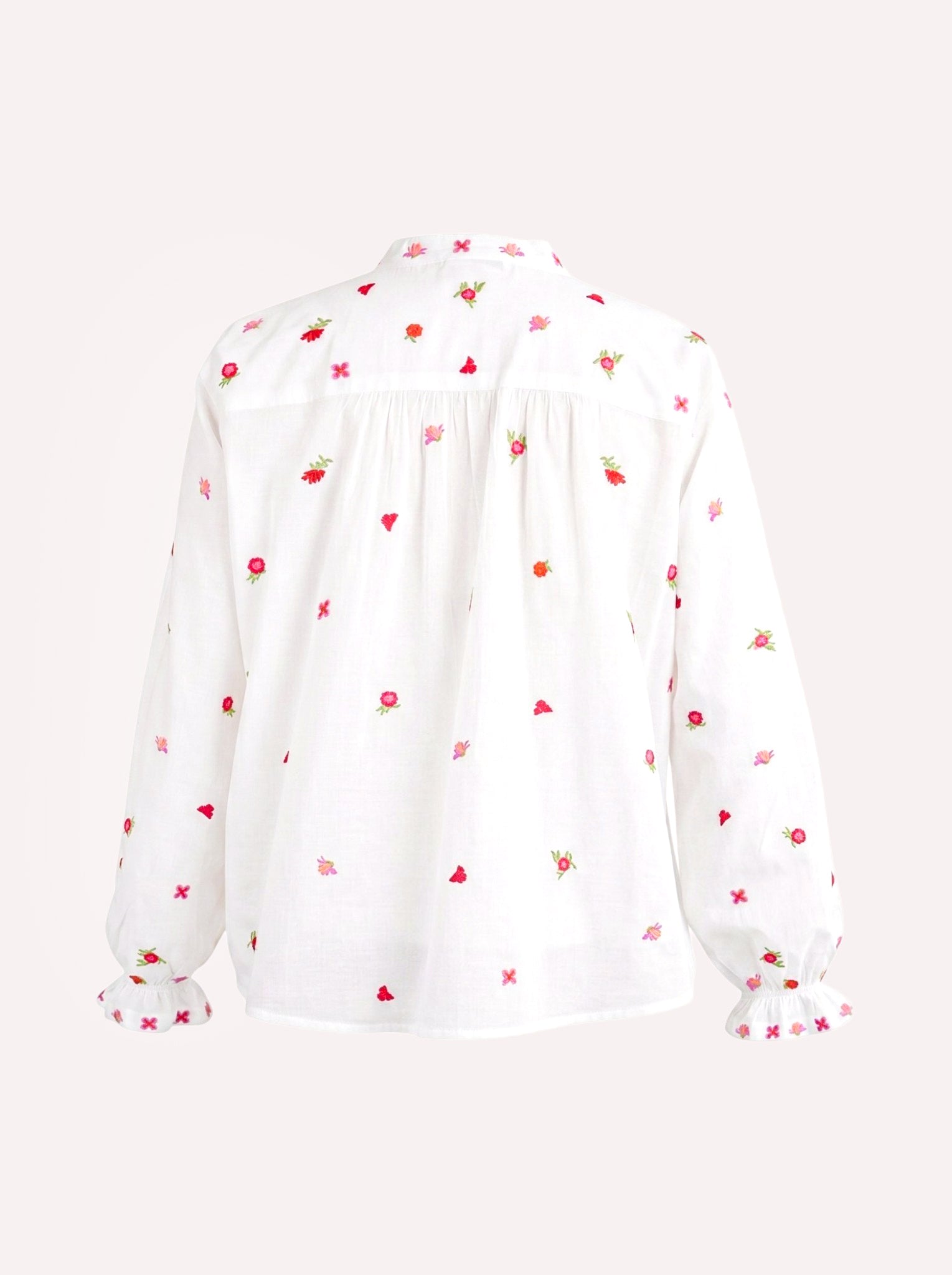A white long-sleeve blouse with a delicate all-over embroidered pattern of small red flowers, green leaves, and pink hearts, shown from the back against a light off-white background.