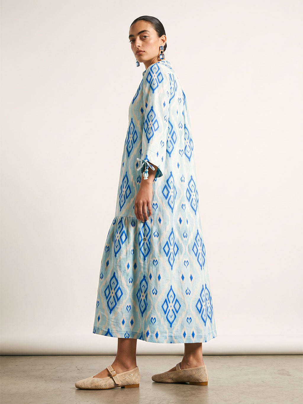 Full-length studio side view of the loose fit bohemian Catmint linen dress in light blue and dark blue ikat print.