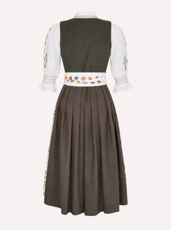Nimo x Münchner Manufaktur dirndl apron with dense green and red floral cross-stitch embroidery from back, styled over a dark green dirndl.