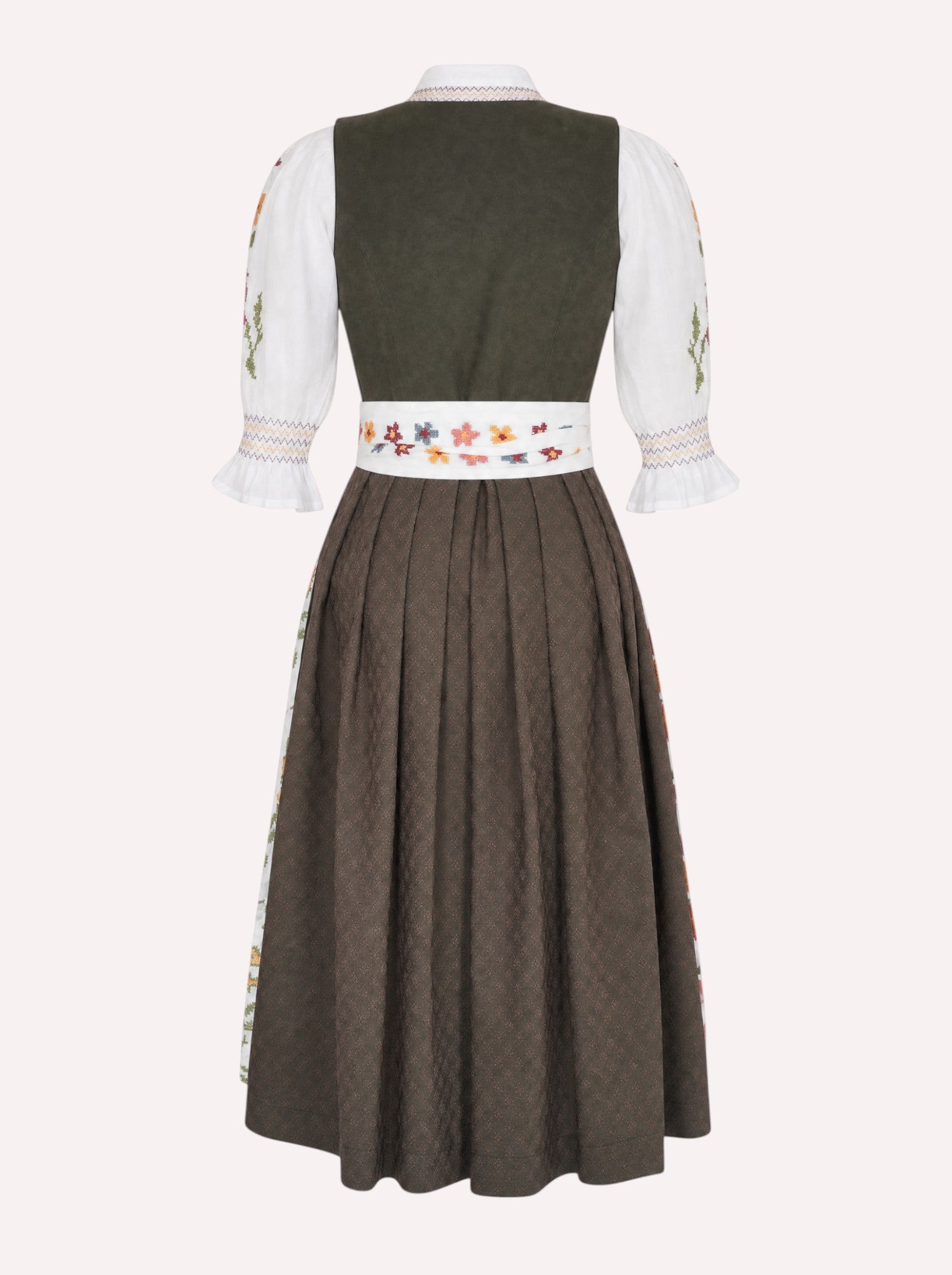 A traditional German dirndl dress shown from the back, featuring a dark olive green bodice, white sleeves with floral embroidery, and a pleated brown skirt with a decorative embroidered waistband.