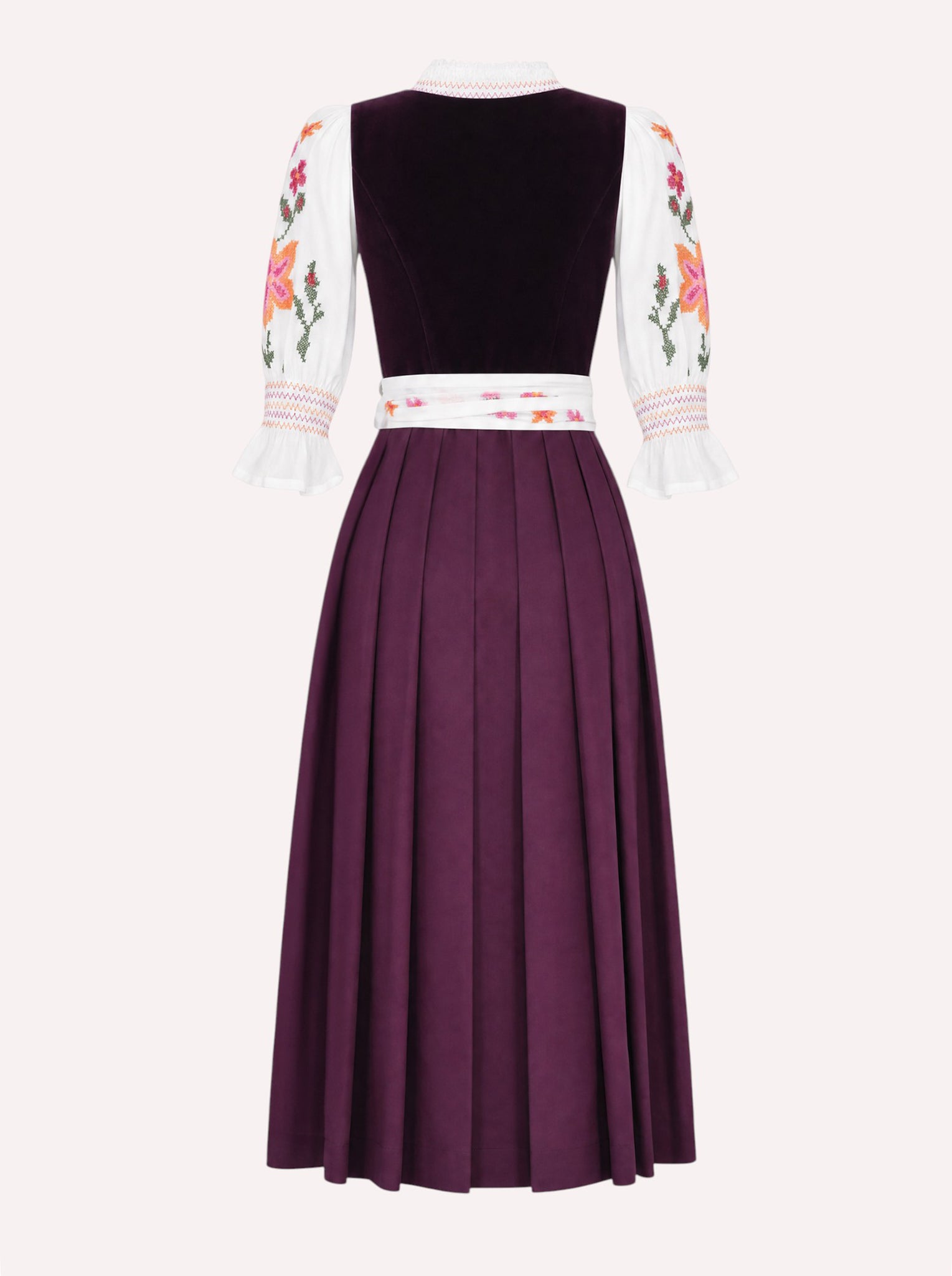 Nimo x Münchner Manufaktur dirndl apron with dense red and orange floral cross-stitch embroidery from back, styled over a burgundy dirndl.
