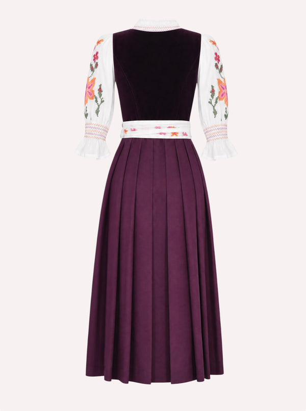 Nimo x Münchner Manufaktur dirndl apron with dense red and orange floral cross-stitch embroidery from back, styled over a burgundy dirndl.