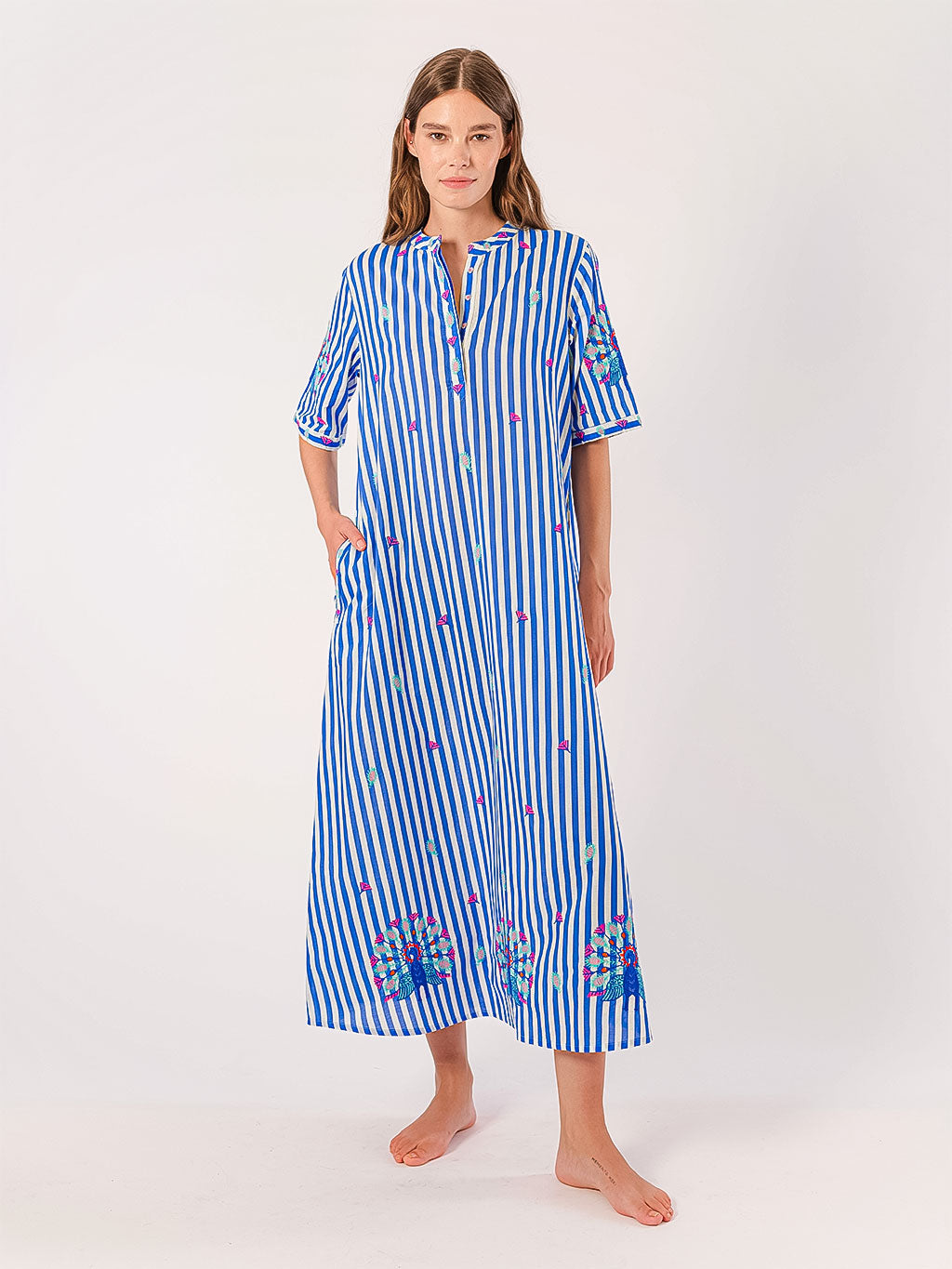 Woman wearing a blue and white striped maxi summer dress with floral embroidery