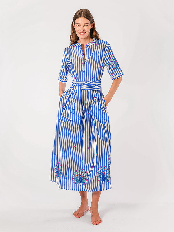 Woman wearing a blue and white striped dress with floral embroidery which is chinched at the waist with a self-tie fabric belt