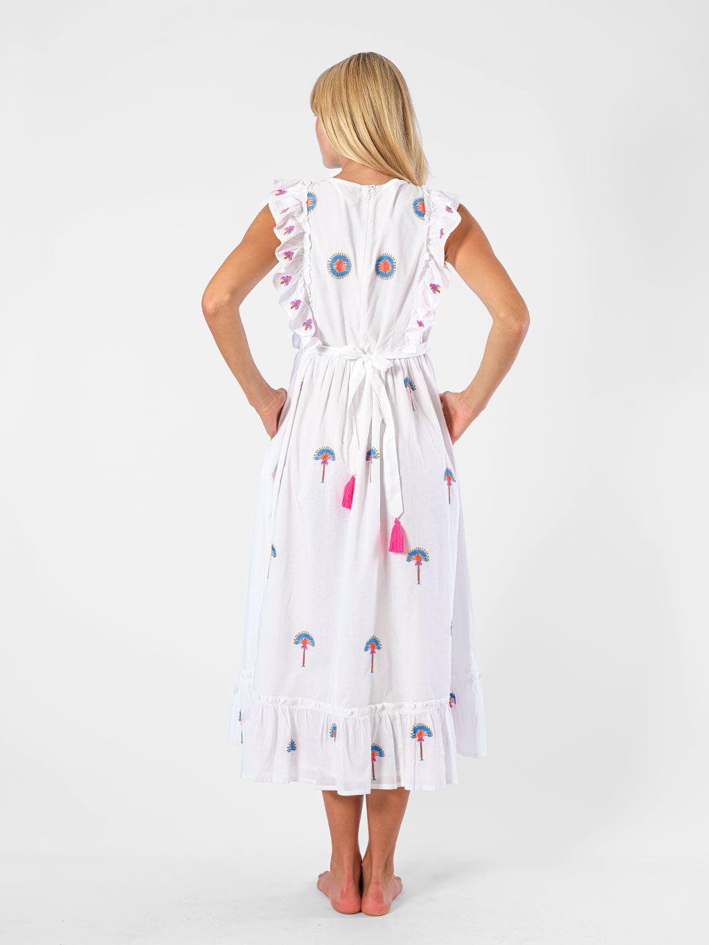 Back view of the Pernilla dress showing the adjustable tie-back with fuchsia tassels and intricate palm tree embroidery.