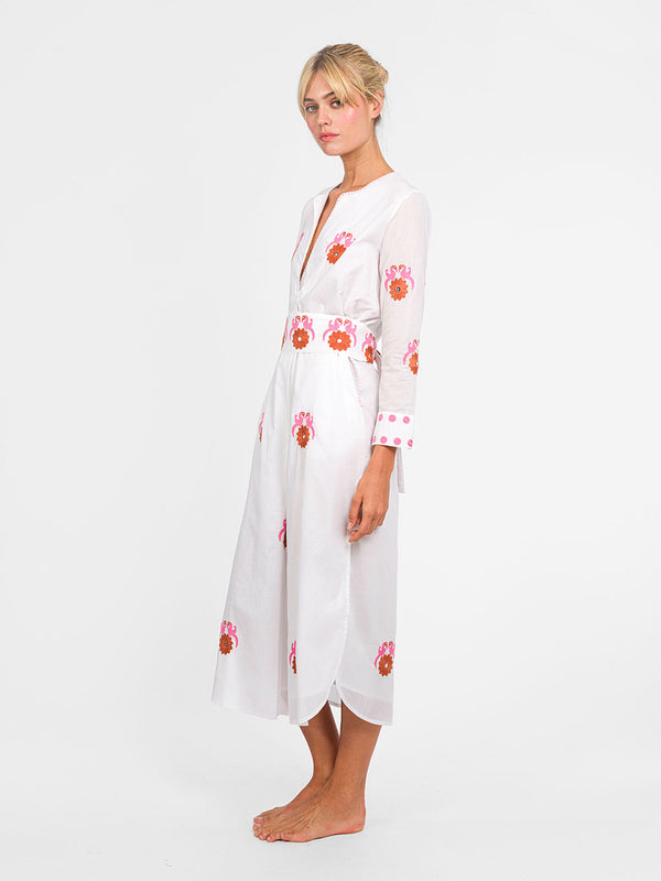Side view of the side slit and the rhythmic bird embroidery along the hem of the white midi dress.